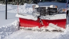 Une camionnette équipée d’un chasse-neige en « v » déblaie la neige d’une allée.