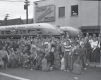 A crowed of boys with duffle bags and their parents stand around two buses packed for a trip.