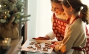 A woman and child putting a sheet of cookies into an oven.