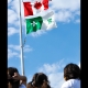 Des enfants regardent les drapeaux canadiens et franco-ontariens hissés.