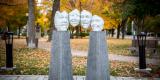 cement pillars hold a row of 4 aluminum sculptural faces