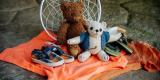 An image of children's stuffed bears and shoes placed on top of an orange shirt.