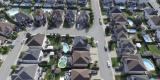 aerial view of houses that all look the same with green grass, pools and streets throughout 
