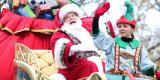 An image of Santa Claus and an elf on a sleigh during a parade. 